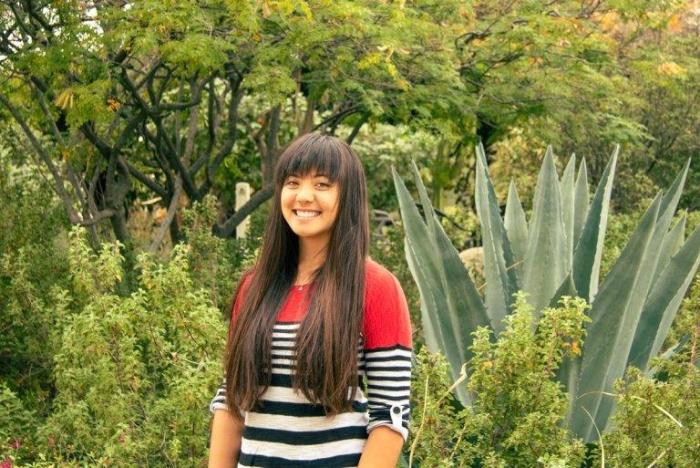 Shelby Ottengheime wears a red, blck, and white striped sweater while standing in front of succulents.